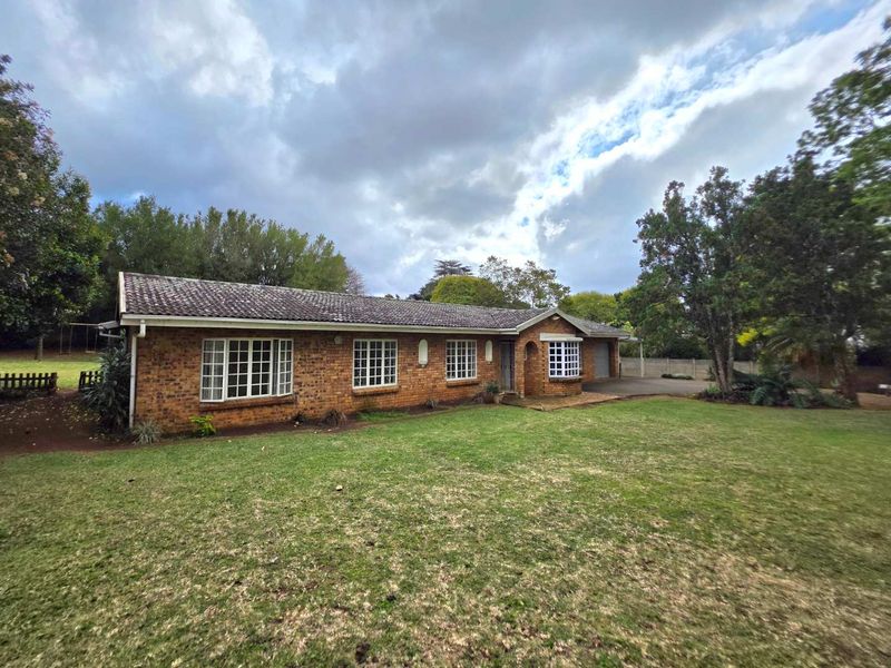 A single-story face-brick family home featuring a tiled roof, bay window, and an attached garage, set on a spacious lawn.