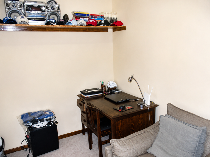 A functional home office space featuring a wall-mounted wooden shelf and neutral wall finishes, suitable for a dedicated workspace.