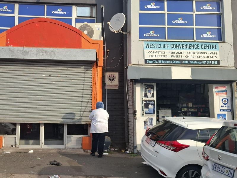 Front facade of a commercial convenience centre featuring a roller shutter door, signage, and an external air conditioning unit.