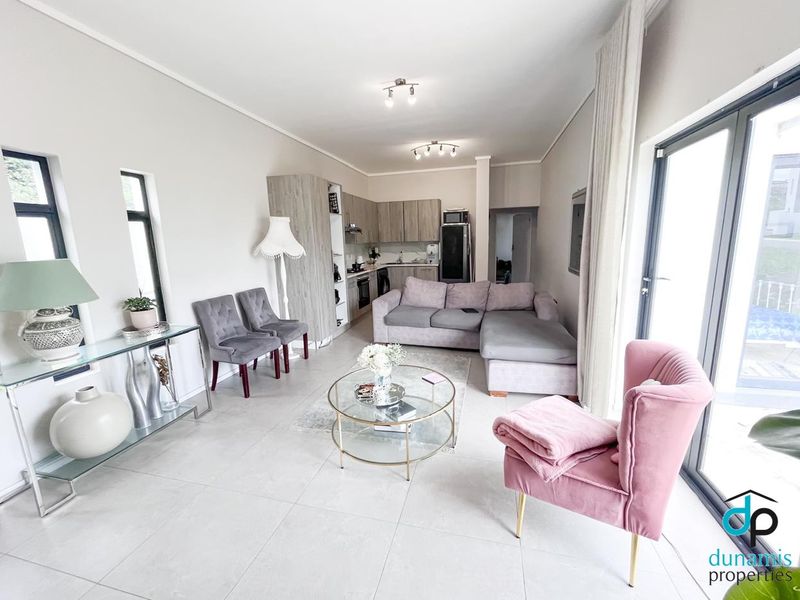 Modern open-plan living area featuring a sleek kitchen with built-in cabinetry and appliances, flowing seamlessly into a bright lounge with large sliding glass doors.
