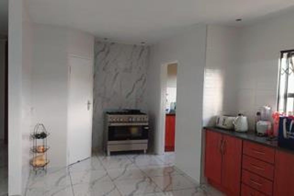 A functional kitchen featuring red cabinetry, marble-look floor tiles, and a built-in gas stove with a marble-effect splashback.