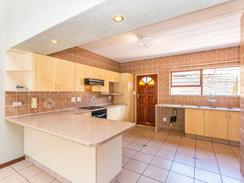 Spacious kitchen featuring light wood cabinetry, tiled backsplash, built-in oven with extractor, and direct access to the exterior.