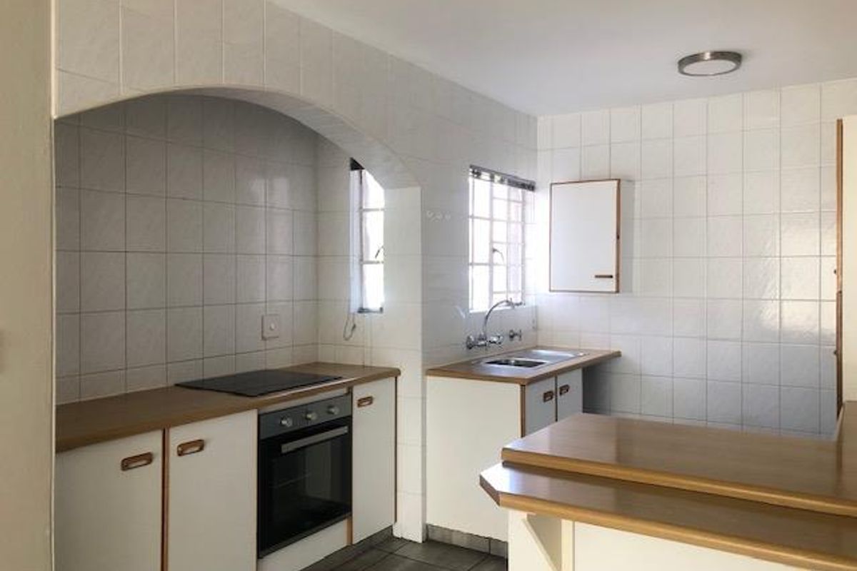 A functional kitchen featuring built-in cabinetry, a fitted oven and hob, tiled splashbacks, and a breakfast bar counter.