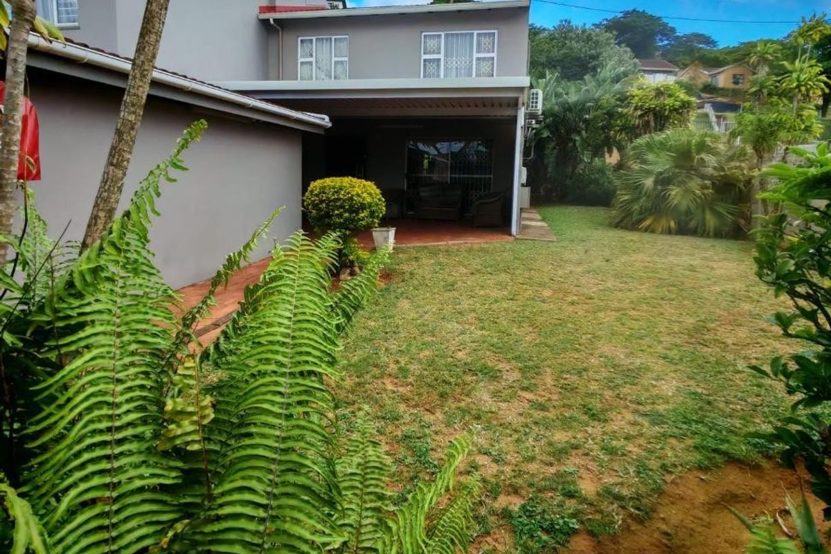 Rear view of the townhouse featuring a covered patio area, paved flooring, and a private garden space.