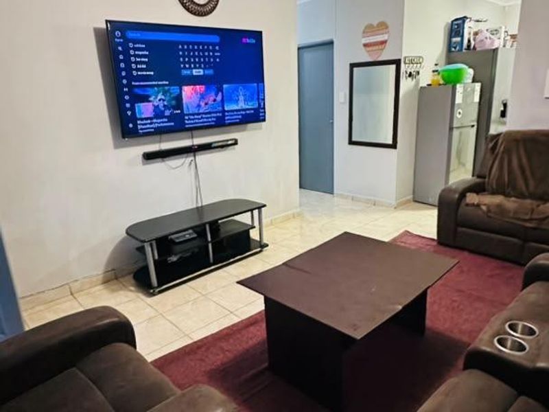 A functional living room featuring tiled flooring and coved ceilings, providing a comfortable space for relaxation and entertainment.