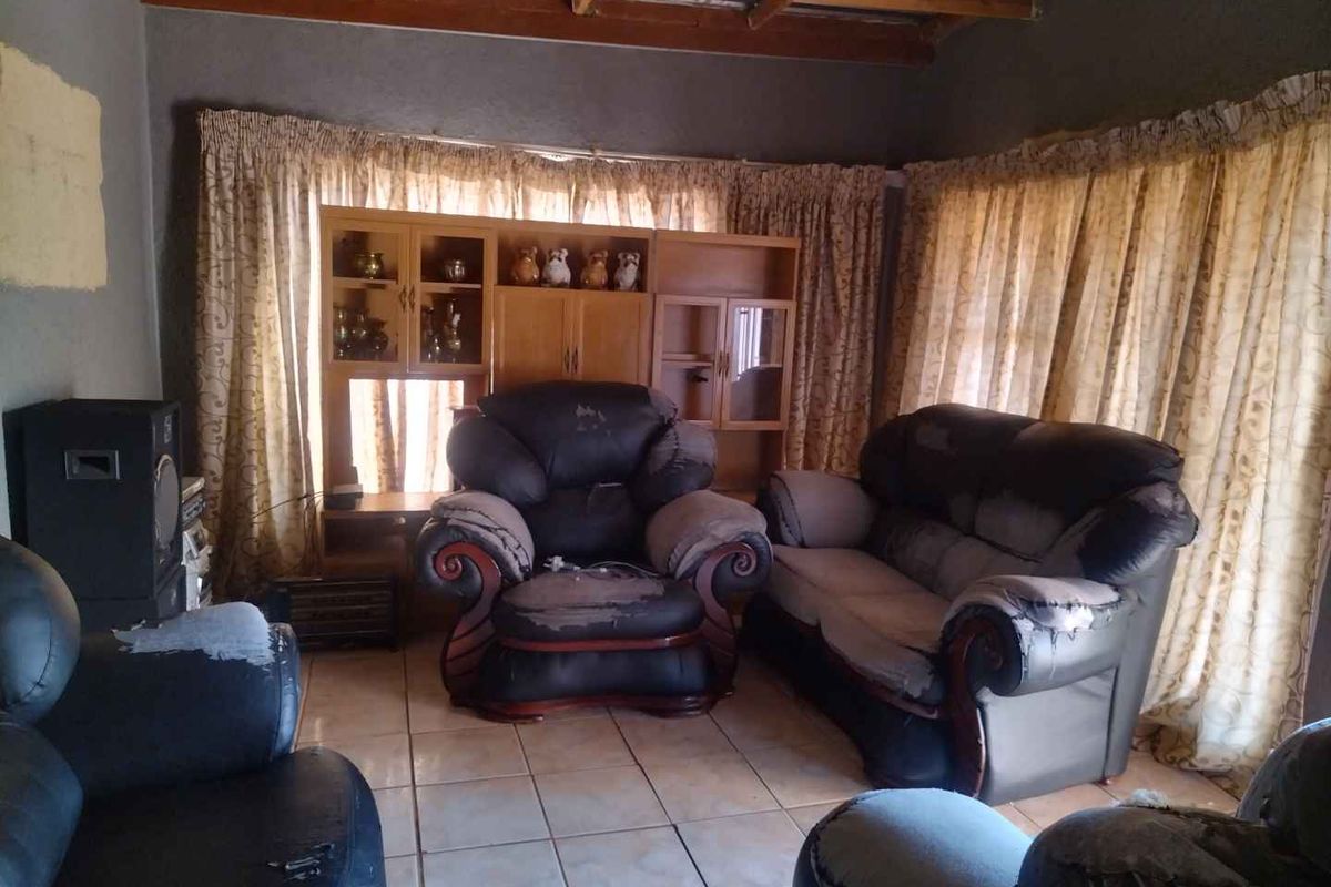 Living room featuring ceramic floor tiles and an exposed timber rafter ceiling, requiring cosmetic updates to improve the overall finish and aesthetic appeal.