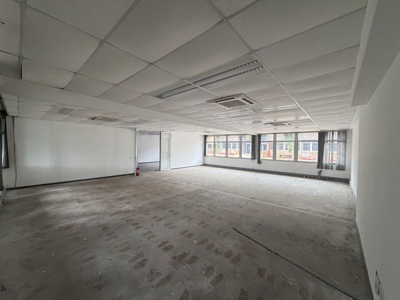 Spacious open-plan office area featuring a suspended ceiling, integrated cassette air conditioning, and large windows providing ample natural light.
