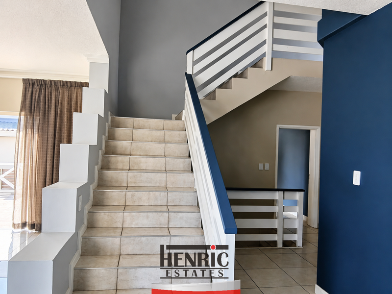 A bright entrance hall featuring a tiled staircase with a white timber balustrade and neutral wall finishes.