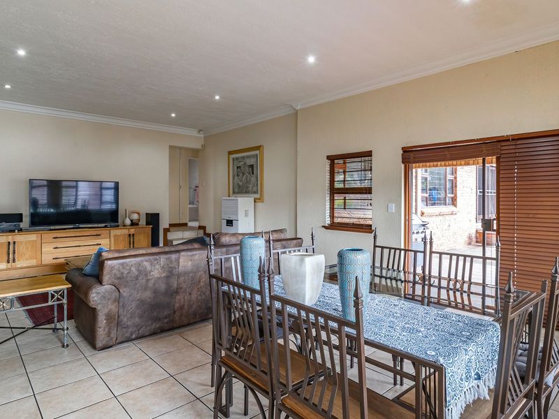Spacious open-plan living and dining area featuring tiled flooring, recessed lighting, and sliding doors leading to an outdoor patio space.