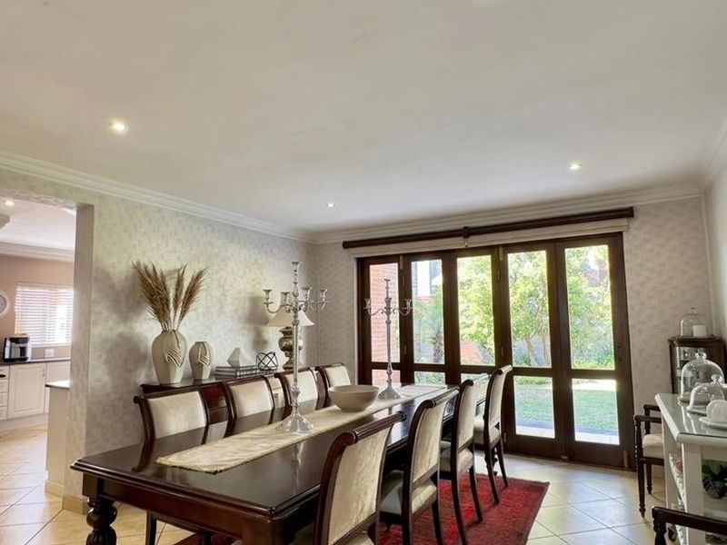 Spacious dining room featuring tiled flooring, recessed lighting, and large timber-framed glass doors providing direct access to the rear garden.