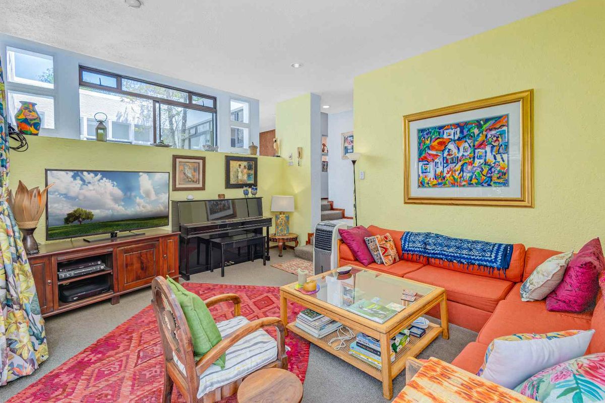 A living room featuring a split-level layout, large windows for natural light, and a staircase leading to an upper level.