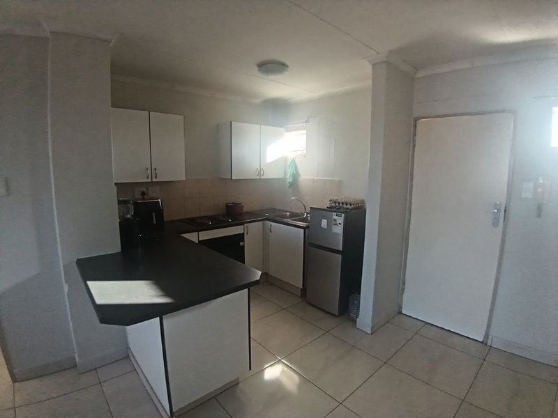 A functional kitchen featuring white cabinetry, dark laminate countertops, tiled flooring, and built-in cooking appliances, offering a practical layout for daily use.
