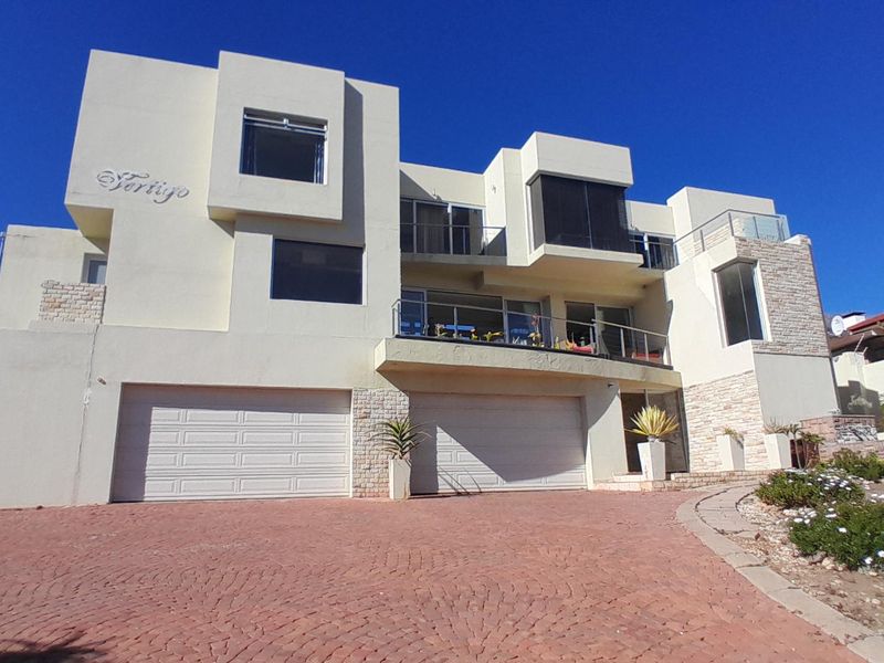 Modern multi-level residential facade featuring a double garage, stone cladding accents, and upper-level balconies with glass balustrades.