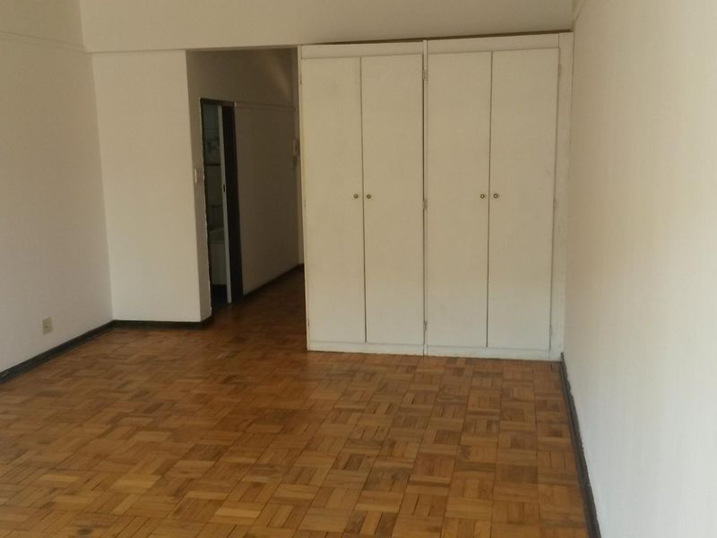 Empty bedroom featuring classic parquet flooring and ample built-in cupboard storage space.