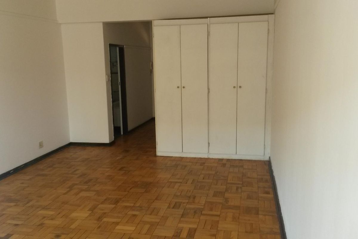 Empty bedroom featuring classic parquet flooring and ample built-in cupboard storage space.
