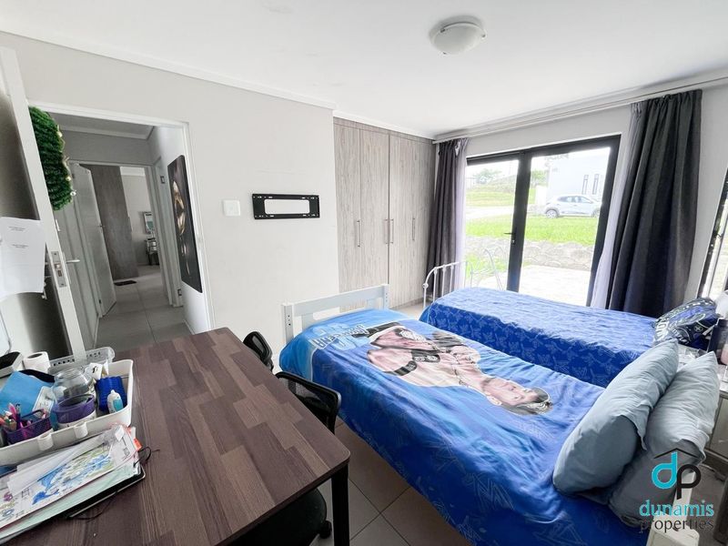 A functional bedroom featuring built-in cupboards, tiled flooring, and a sliding glass door providing direct access to the exterior.