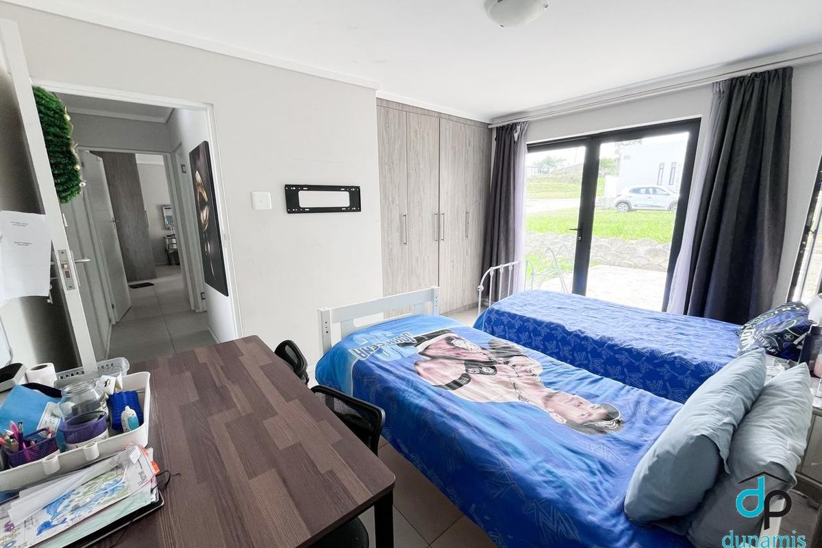 A functional bedroom featuring built-in cupboards, tiled flooring, and a sliding glass door providing direct access to the exterior.