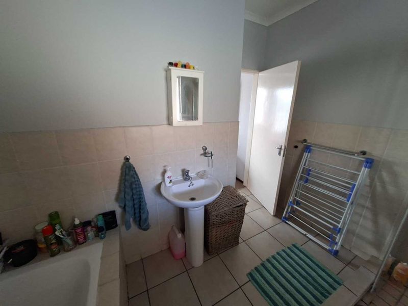 A functional bathroom featuring a pedestal basin, tiled splashback, and tiled flooring, providing a clean and practical space.