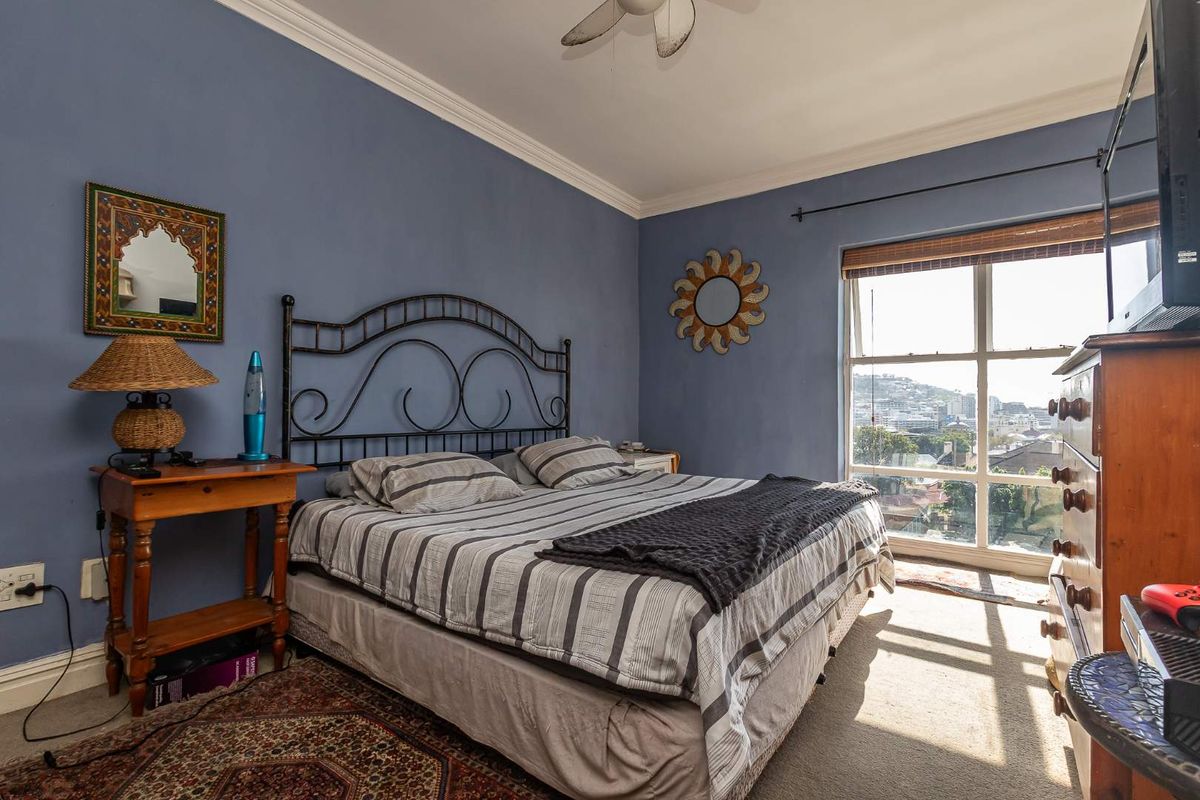 A bedroom featuring a large window with city views, crown molding, and a ceiling fan.