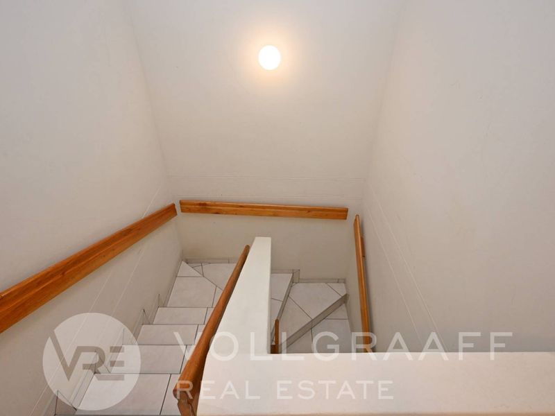 A functional staircase area featuring tiled steps and wooden handrails, providing access between levels within the townhouse.