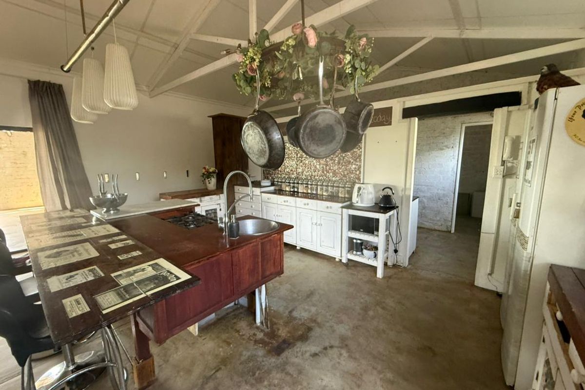 Rustic farmhouse kitchen featuring a central wooden island, exposed vaulted ceiling beams, and a tiled backsplash, offering a character-filled prep and cooking space.