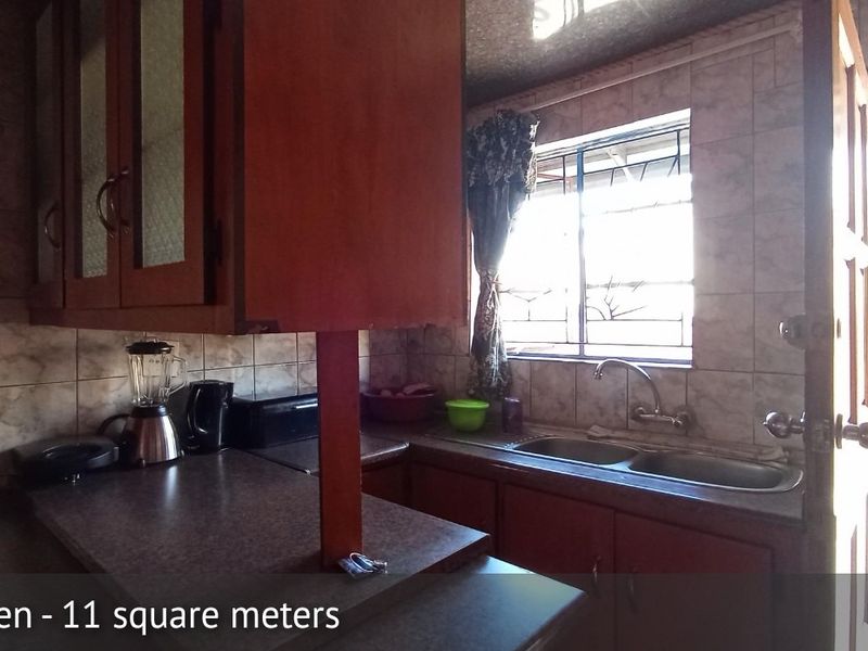 A functional kitchen featuring built-in wooden cabinetry, a double bowl sink, and tiled wall finishes, providing a practical workspace with natural light.