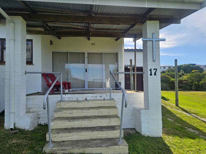 Front entrance featuring a covered porch with concrete stairs, metal handrails, and sliding glass door access to the home.