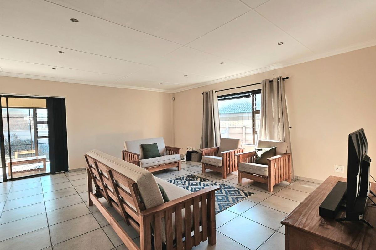 Spacious living room featuring neutral walls, tiled flooring, recessed lighting, and large sliding glass doors providing access to the outdoor area.