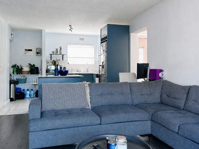 Open-plan living area featuring a kitchen with island, cabinetry, and a seamless transition to the lounge space with laminate flooring.