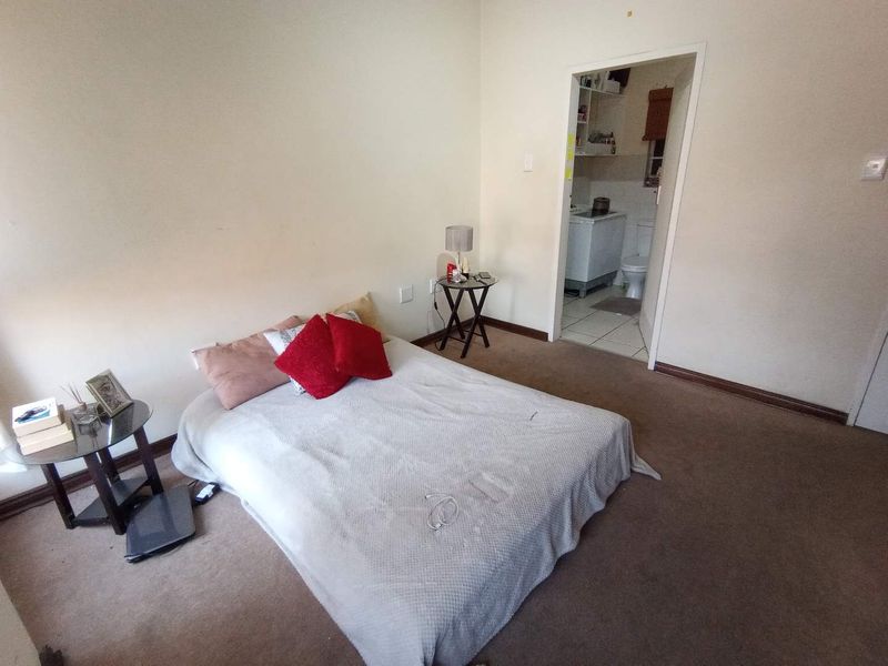 A carpeted bedroom featuring neutral walls and direct access to an adjoining bathroom area.