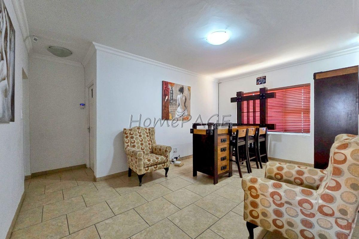 A living area featuring tiled flooring, recessed ceiling lighting, and fitted window blinds.