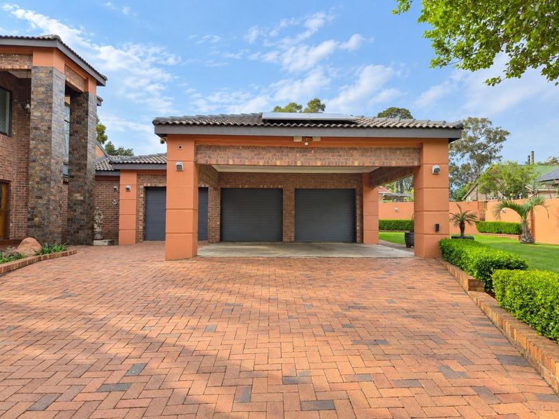 A spacious double garage featuring brick pillars, tiled roofing with solar panels, and a well-maintained brick paved driveway.