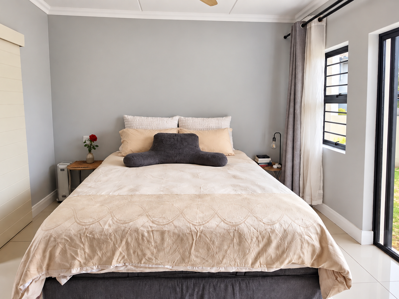A well-maintained bedroom featuring neutral walls, tiled flooring, and a large sliding door providing direct access to the garden area.