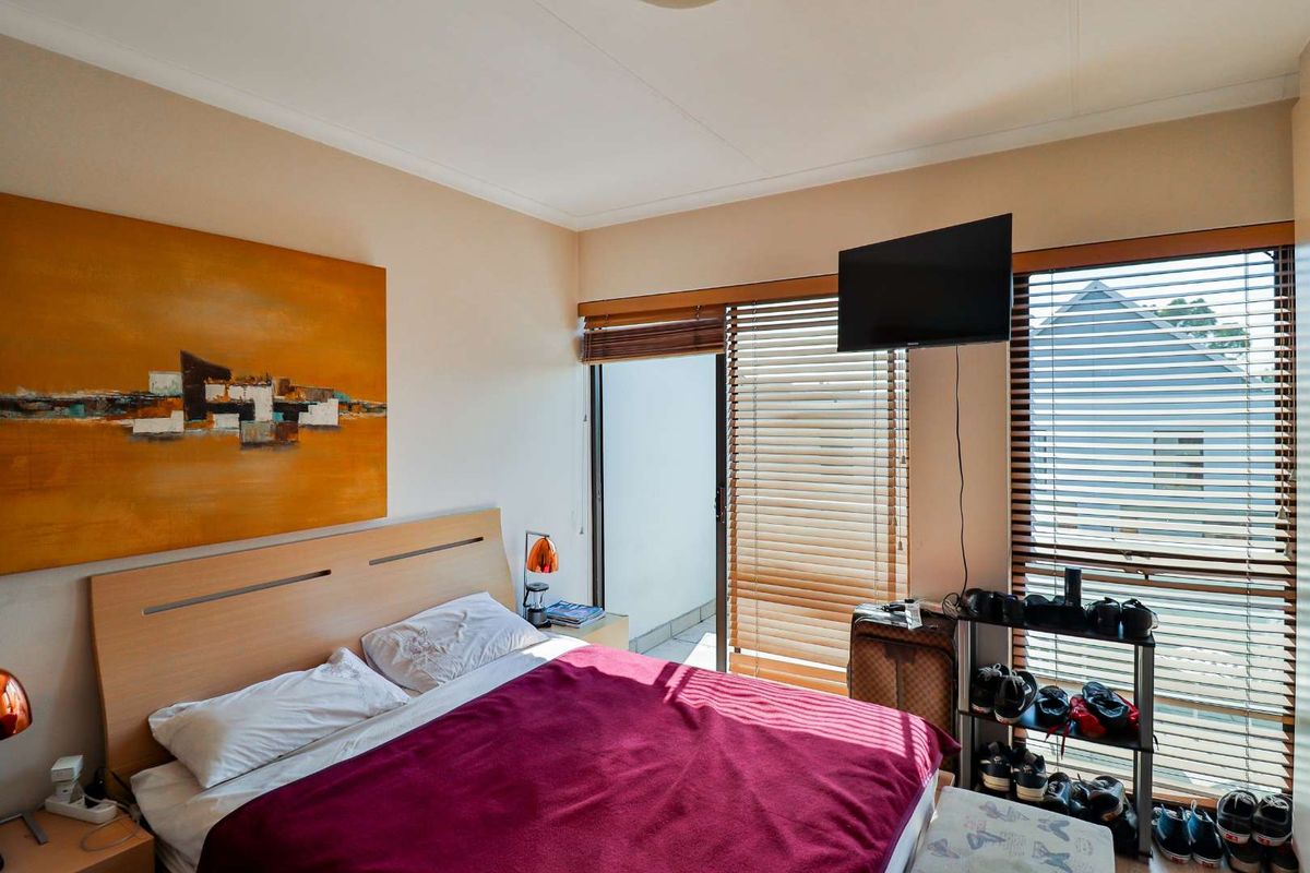 A bedroom featuring a sliding glass door with venetian blinds, providing access to an outdoor area and natural light.