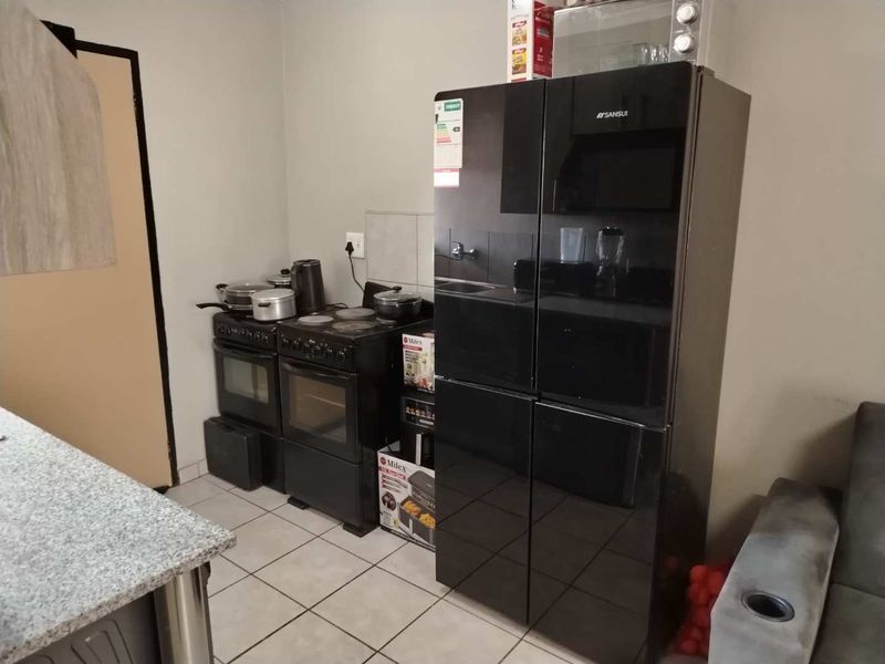 A functional kitchen area featuring tiled flooring, granite countertops, and a freestanding stove, providing a practical space for meal preparation.