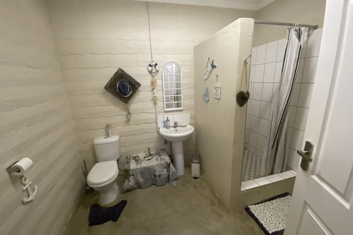 A functional bathroom featuring a pedestal sink, toilet, and a walk-in shower with tiled enclosure and curtain.