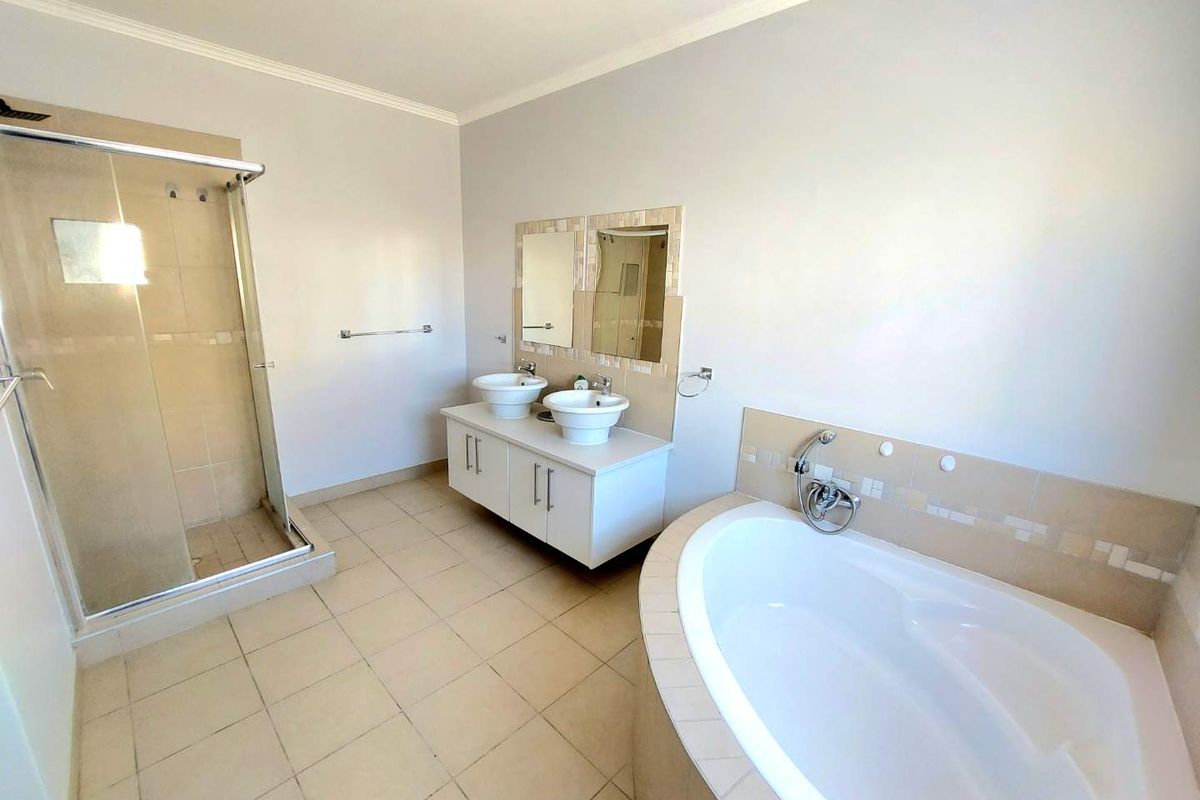 Spacious bathroom featuring a corner bathtub, a separate glass-enclosed shower, and a double vanity with vessel sinks.