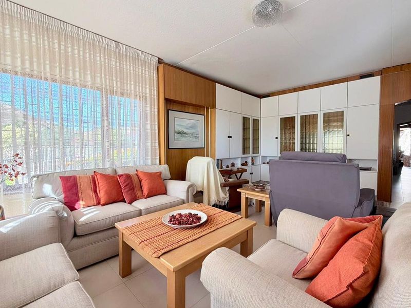 A comfortable living room featuring extensive built-in cabinetry, tiled flooring, and large windows that provide ample natural light.