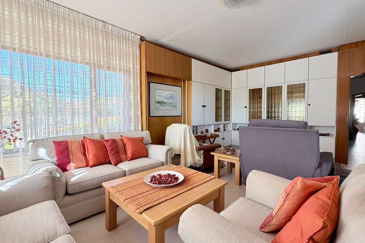 A comfortable living room featuring extensive built-in cabinetry, tiled flooring, and large windows that provide ample natural light.