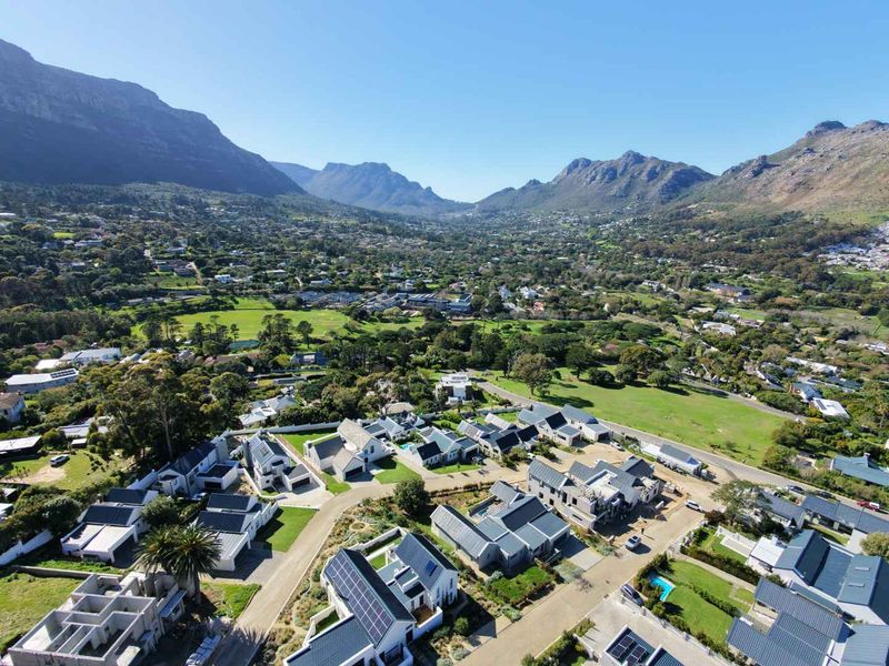 An aerial view of a residential estate featuring modern homes with solar panels, set against a scenic mountain backdrop.