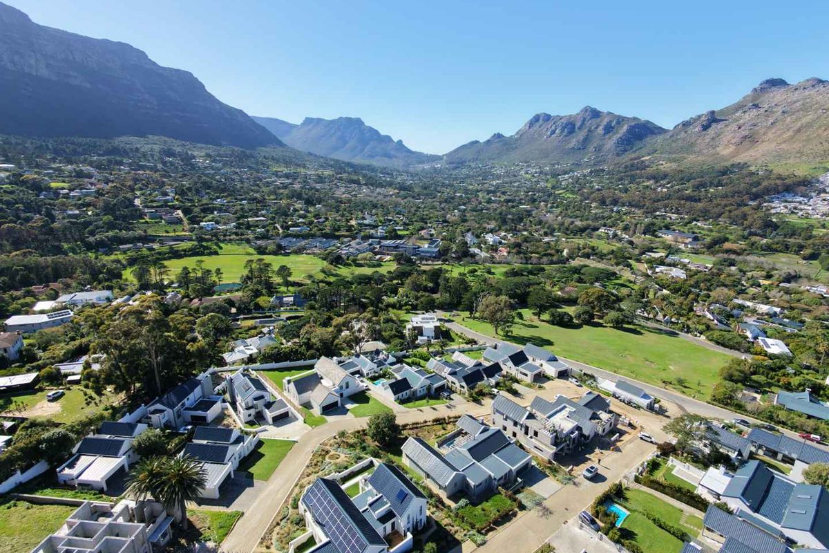 An aerial view of a residential estate featuring modern homes with solar panels, set against a scenic mountain backdrop.