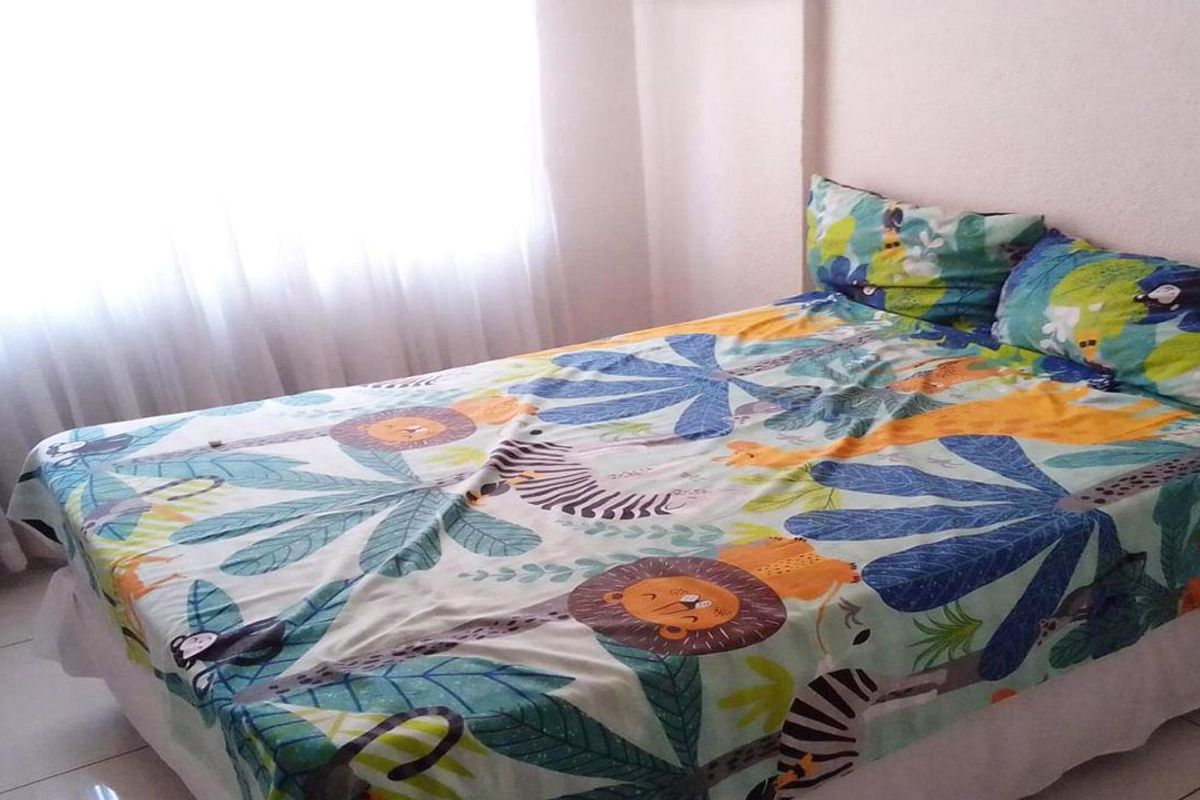 A bedroom featuring tiled flooring and a large window with sheer curtains, providing natural light to the space.