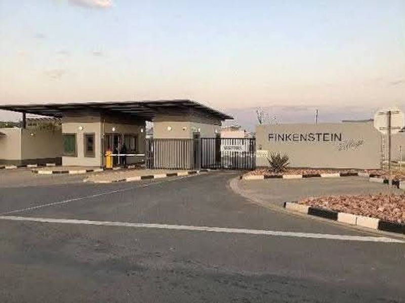 The main entrance and security gatehouse of Finkenstein Village, featuring a controlled access boom gate and professional signage.