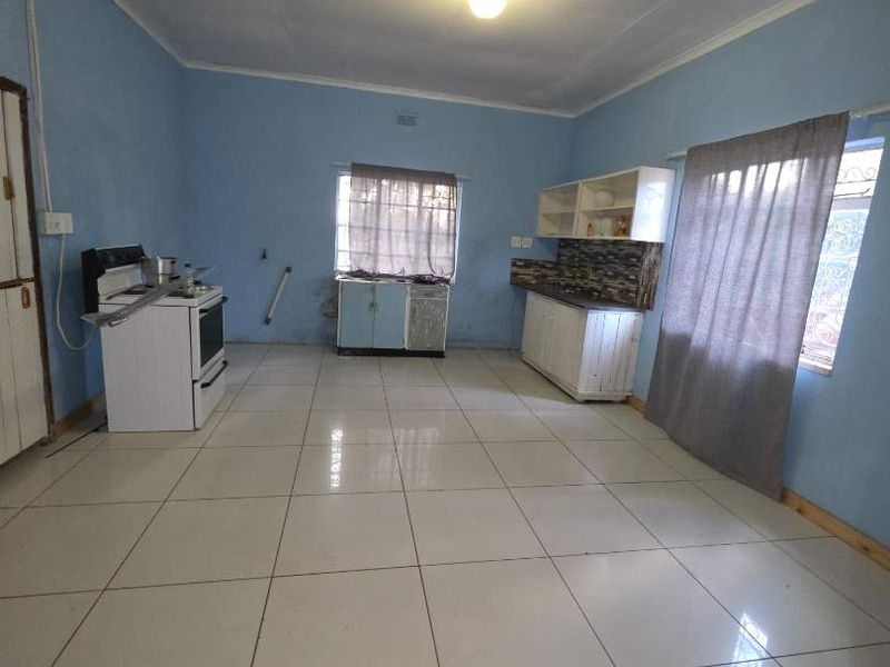 A functional kitchen space featuring tiled flooring, freestanding stove, and basic cabinetry. The area offers potential for modernization and improved layout design.
