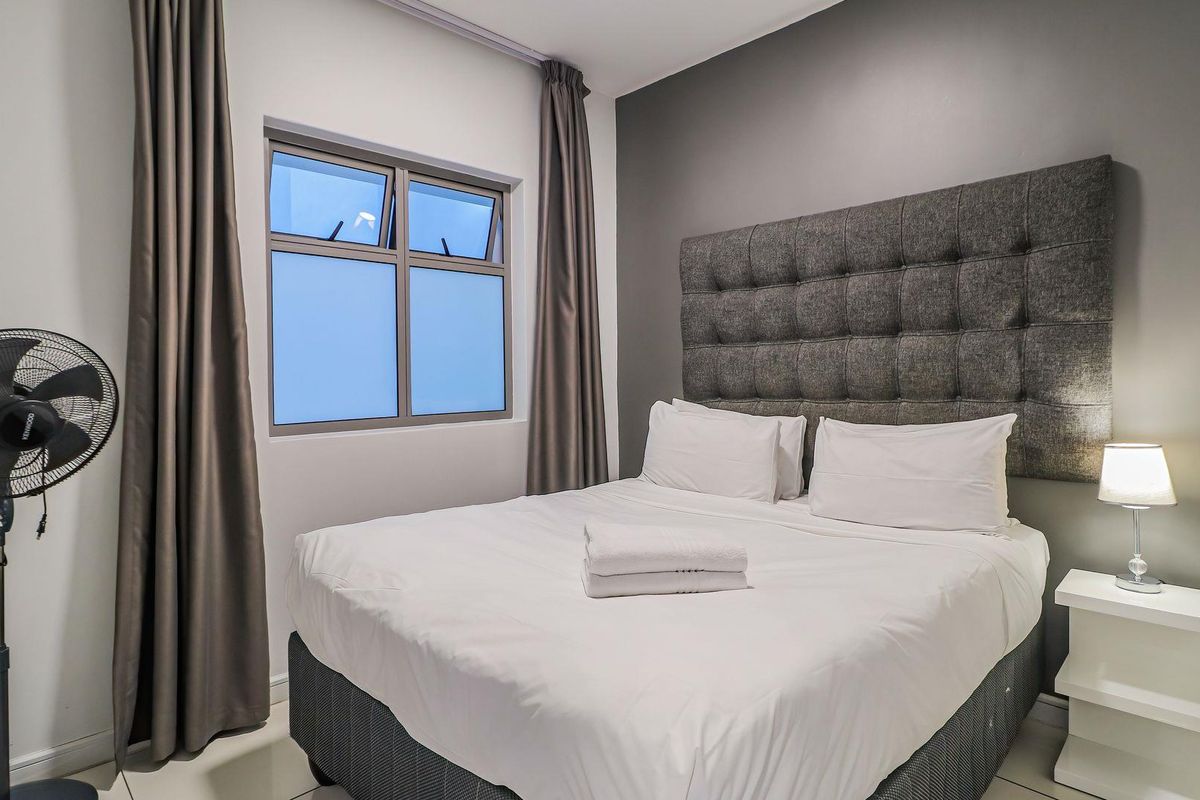 A well-maintained bedroom featuring a modern upholstered headboard and neutral finishes, providing a comfortable and clean sleeping space.