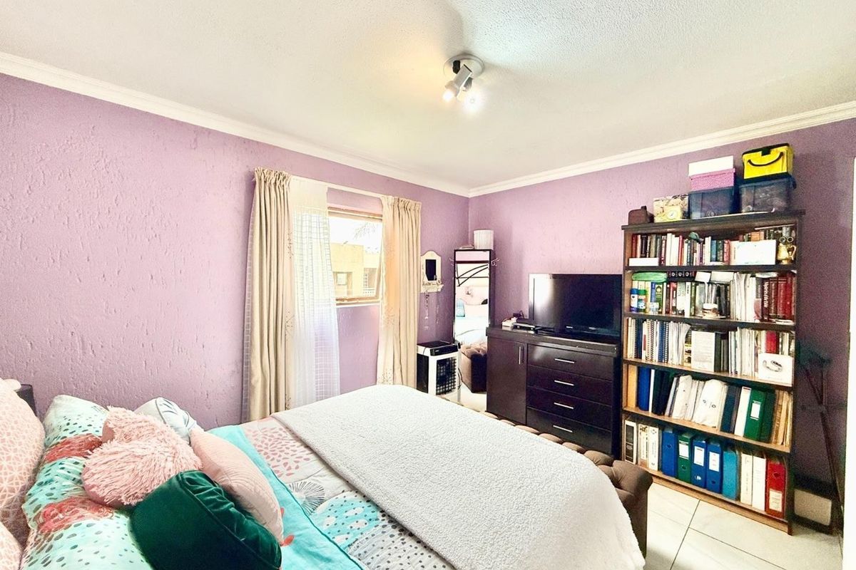 A bedroom featuring tiled flooring, textured walls, and a ceiling-mounted light fixture.