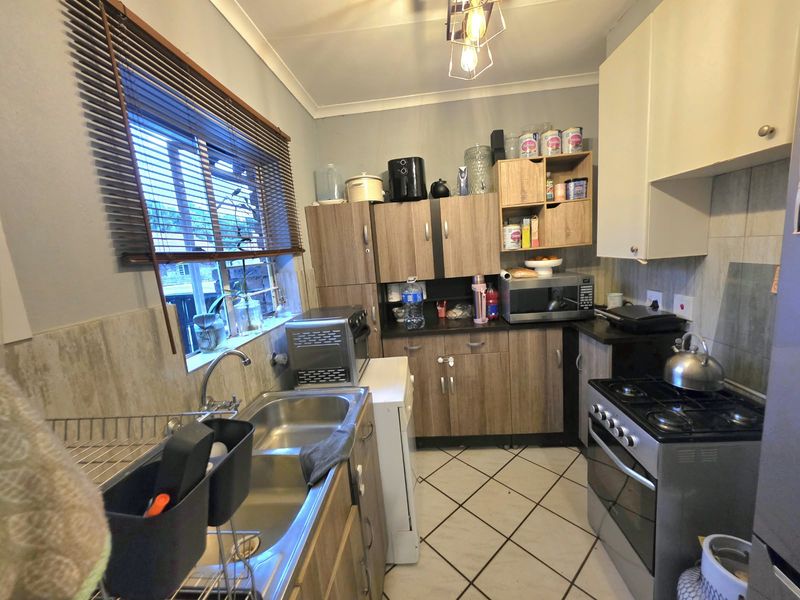Compact kitchen featuring laminate cabinetry, double bowl stainless steel sink, gas stove, and tiled flooring with a window providing natural light.