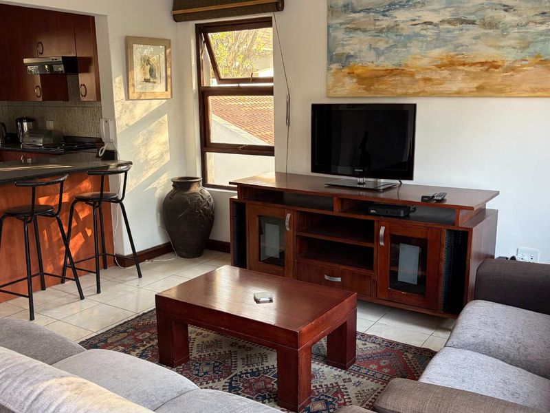 Open-plan living area featuring a kitchen with granite countertops and tiled flooring, seamlessly connected to a comfortable lounge space.