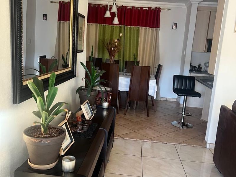 Open plan living and dining area featuring tiled flooring, coved ceilings, and a functional kitchen with a breakfast counter.