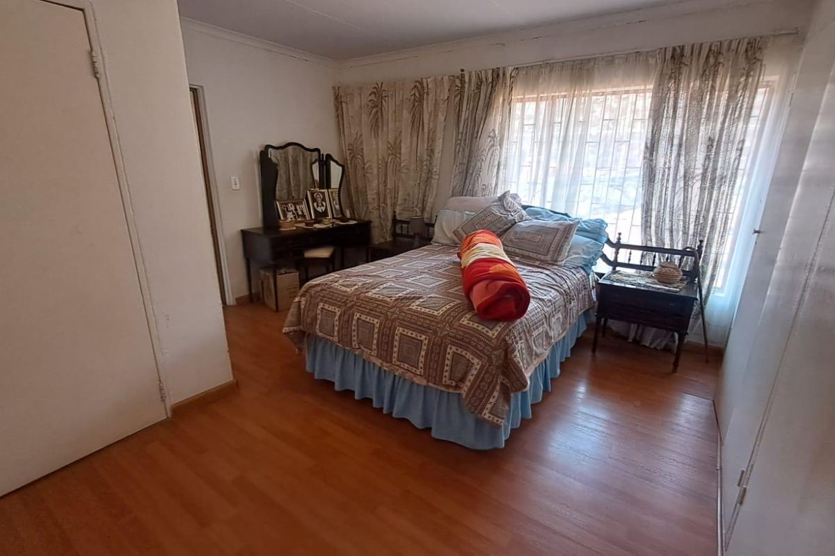 A bedroom featuring laminate flooring and built-in cupboards, offering a functional space with natural light through the window.